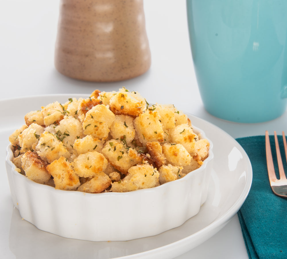 Herb seasoned stuffing in a white bowl, speckled with green herbs