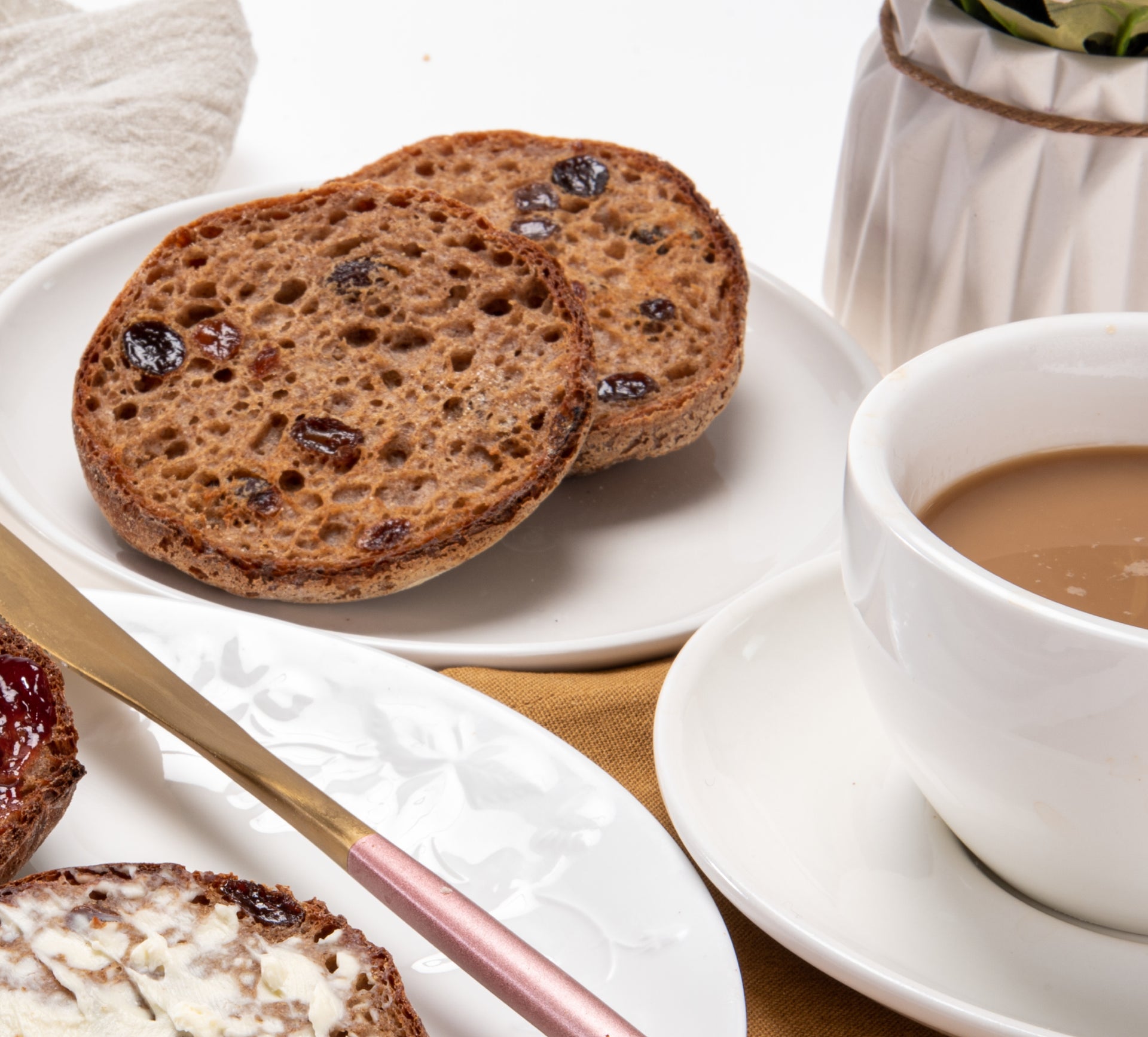 Cinnamon raisin English muffin half with raisins, served on a white plate