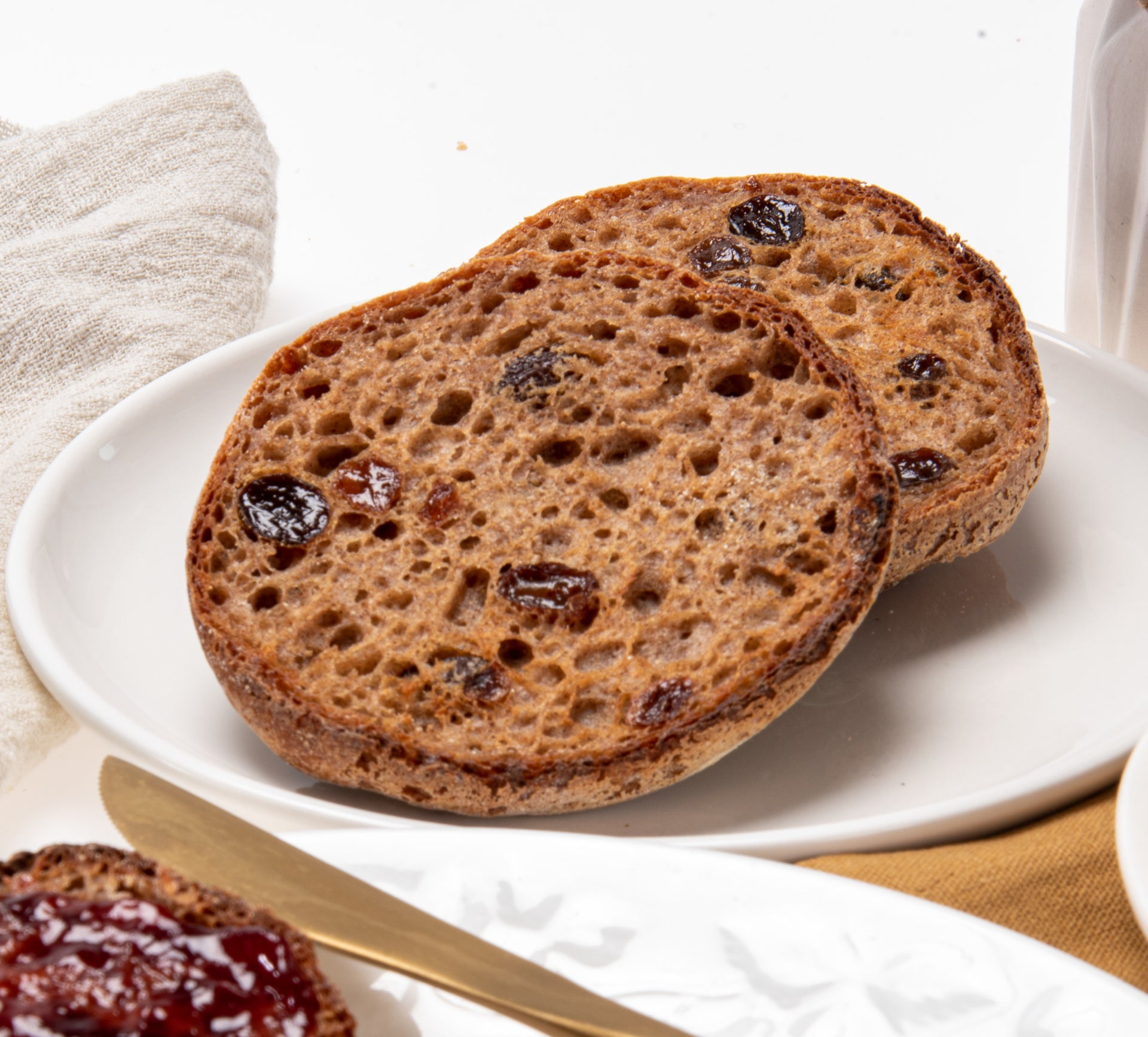 Cinnamon raisin English muffin half with visible raisin bits on a white plate